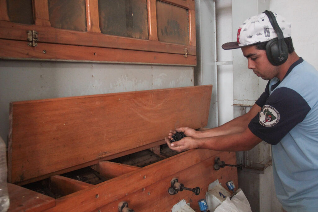 Trabalhador em cooperativa rural durante beneficiamento para investir com impacto